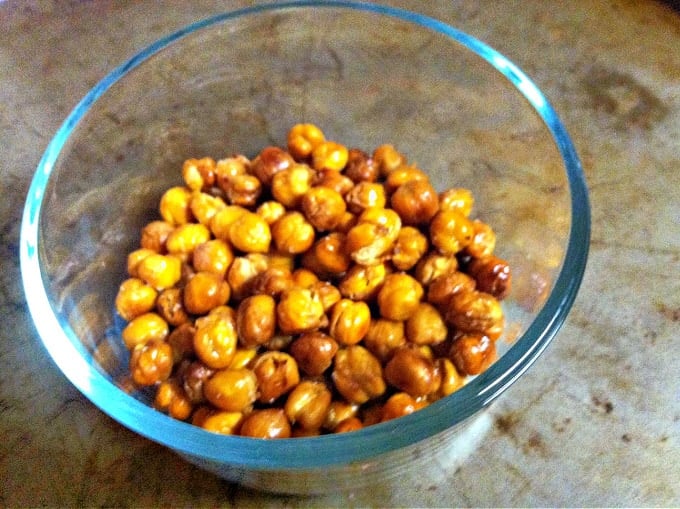 glass bowl of roasted garbanzo beans on a baking sheet