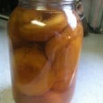 A jar of peaches, perfect for Peach Cake, sitting on a counter.