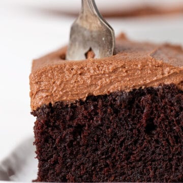 A piece of chocolate stout cake on a plate with a fork.