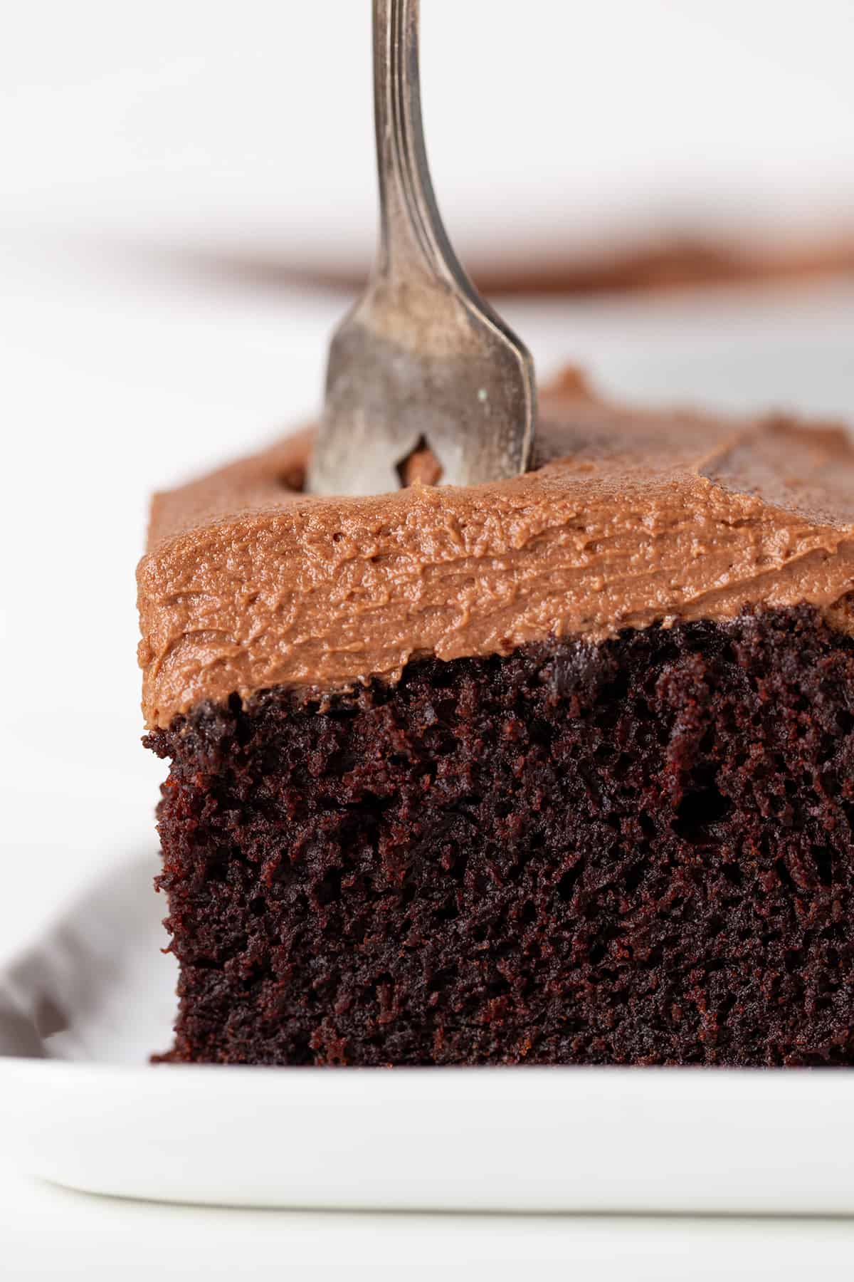 A piece of chocolate stout cake on a plate with a fork.