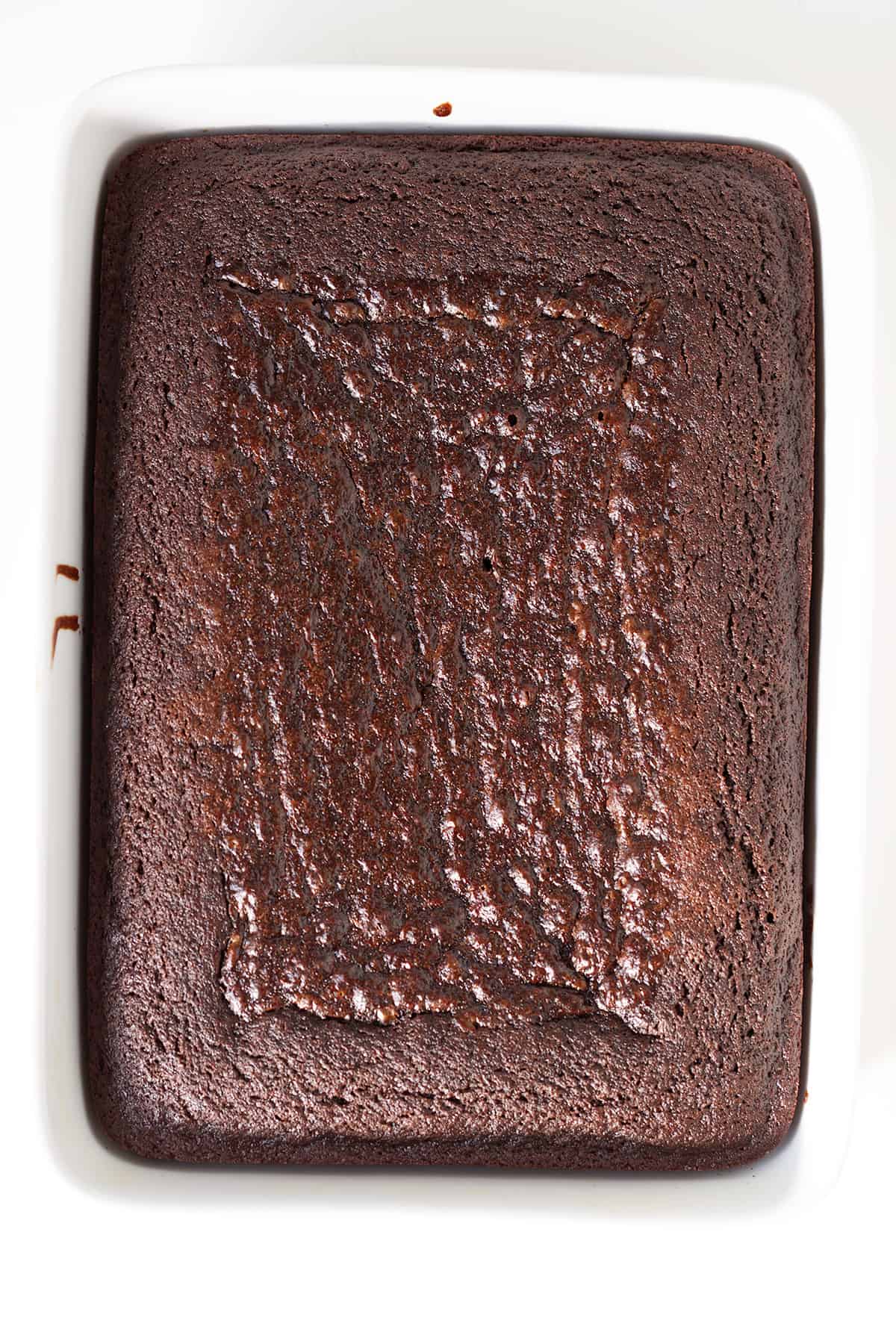 Chocolate stout cake in a square dish on a white surface.