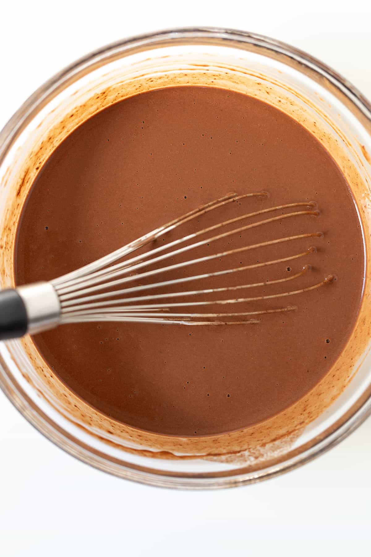 A bowl of chocolate stout cake batter with a whisk in it.