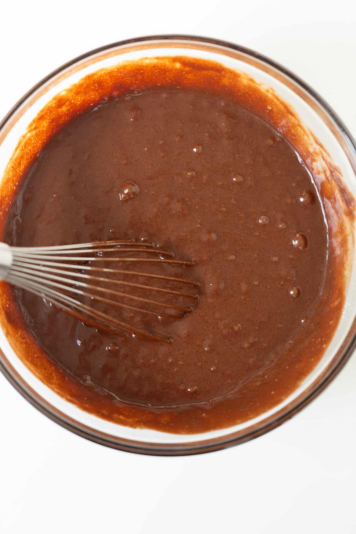 A bowl of chocolate stout sauce with a whisk in it.