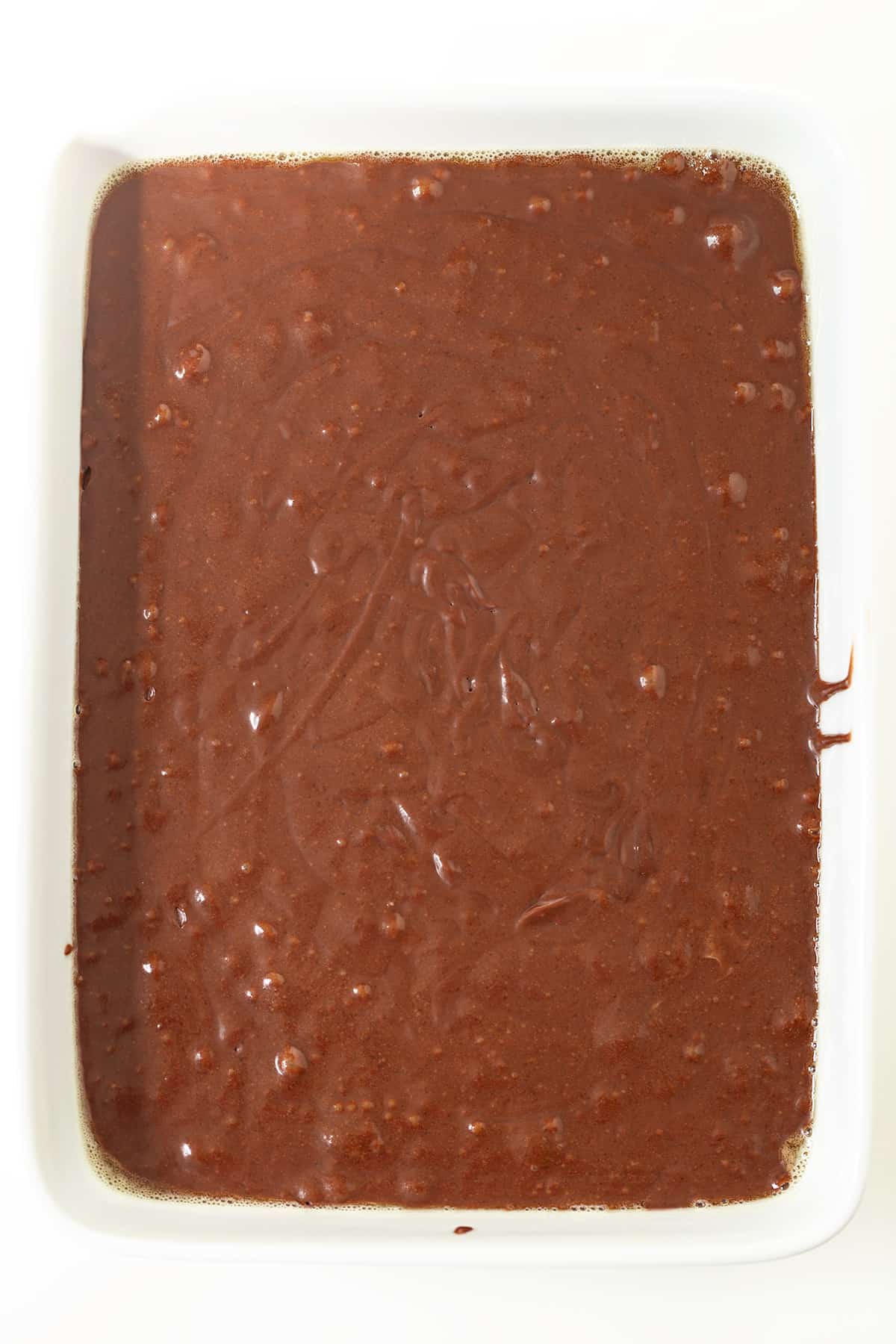 A square of chocolate stout cake on a white surface.