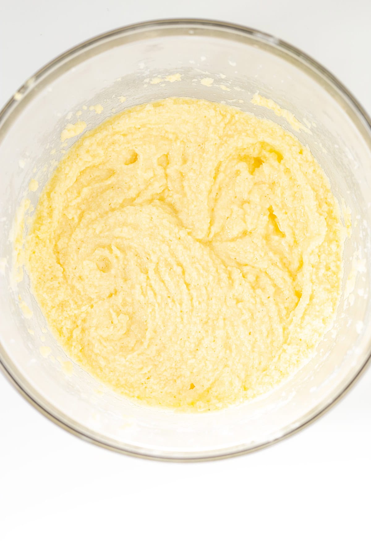 A glass bowl containing creamy, pale yellow cake batter or dough, mixed and ready for the next baking step of delicious Oreo Cookies and Cream Cupcakes.