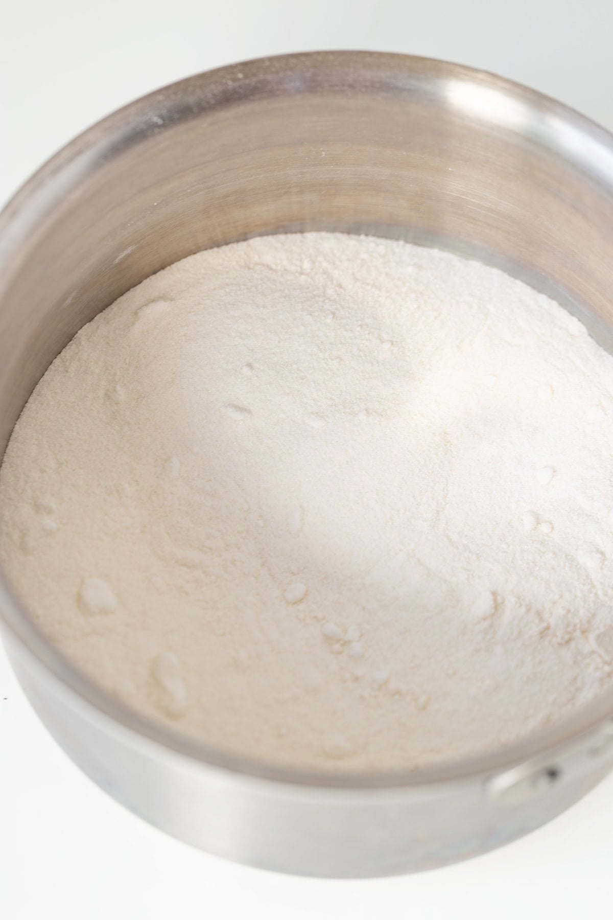 A metal mixing bowl filled with a mound of white flour on a white surface, ready to create delicious Oreo Cookies and Cream Cupcakes.