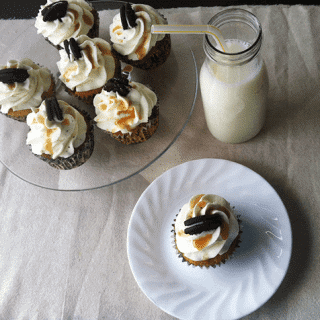 A plate of Oreo Cookies and Cream cupcakes, accompanied by a glass of milk.