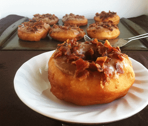 A table with a plate of Maple Glazed Yeast Donuts.