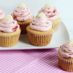 White chocolate cupcakes with strawberry icing on a pink plate.