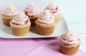 White chocolate cupcakes with strawberry icing on a pink plate.