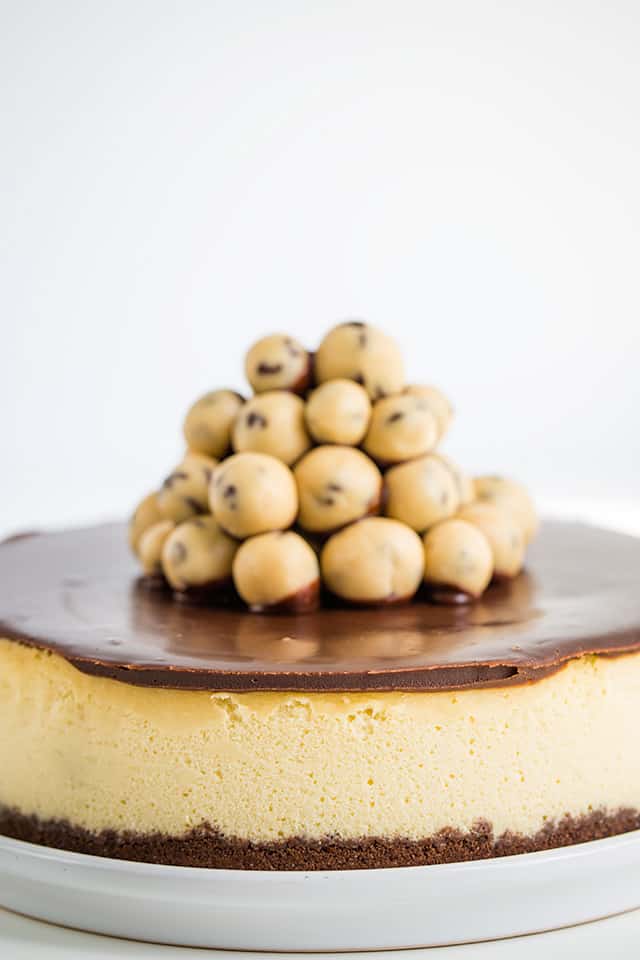 Closeup of the side of the cheesecake on a white plate with a stack of cookie dough in the center
