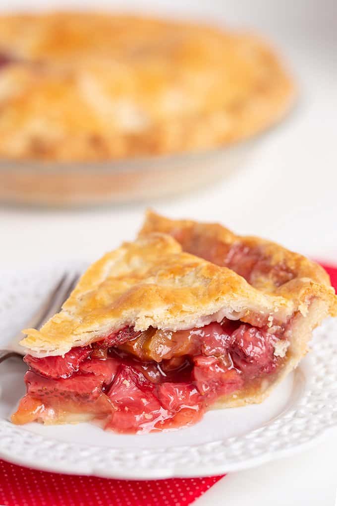 slice of pie on a white plate with the rest of the pie behind it 