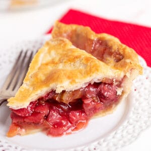 square image of a slice of pie on a white plate with a fork