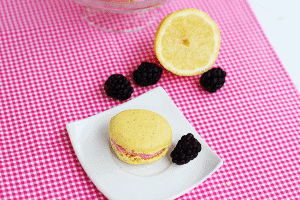 A plate with lemon macarons and blackberries, topped with mixed berry buttercream.