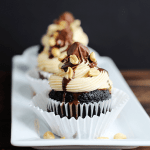 Snickers Cupcakes with a black and dark wooden background.