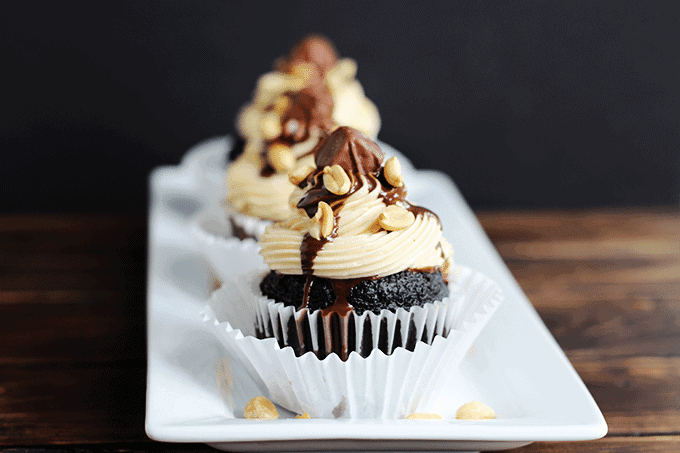 Snickers Cupcakes with a black and dark wooden background.