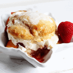 A white bowl with a scoop of ice cream and a strawberry.