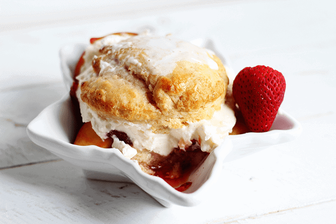 A white bowl with a scoop of ice cream and a strawberry.