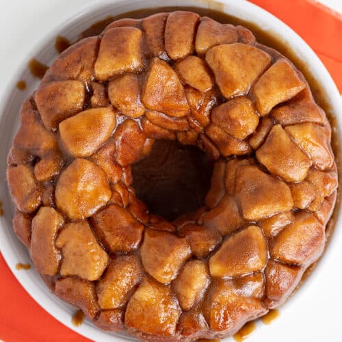 overhead photo of monkey bread on a white plate with an orange fabric under it