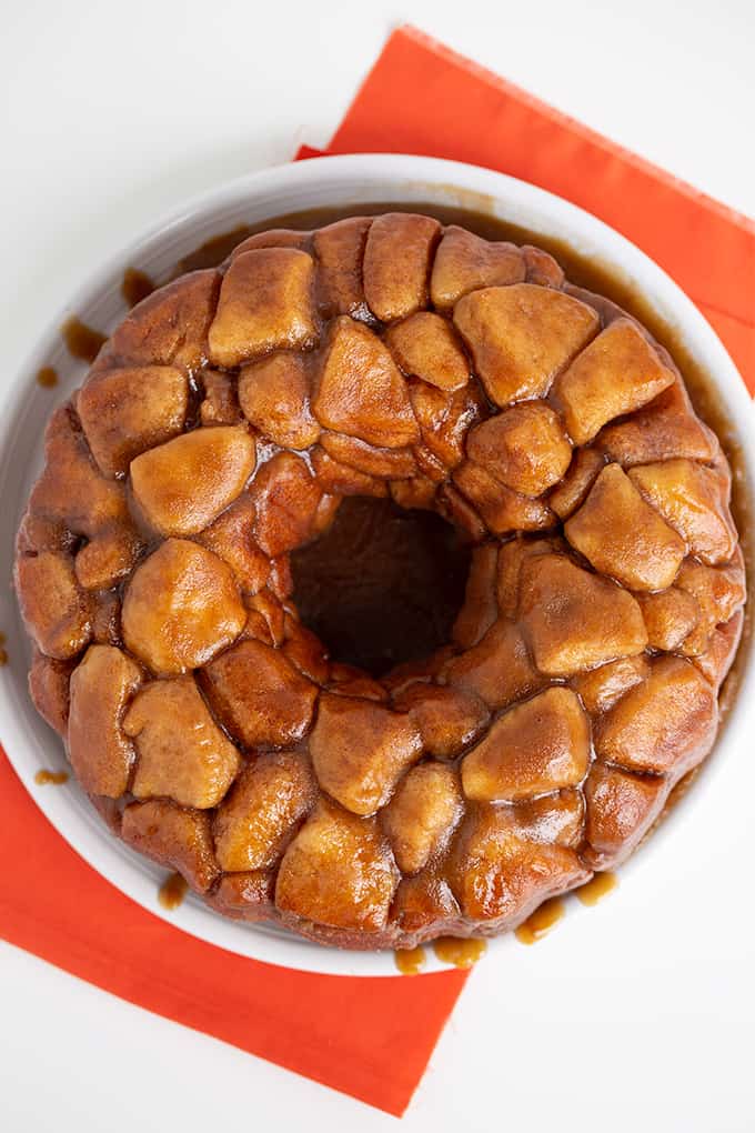 overhead photo of monkey bread on a white plate with an orange fabric under it