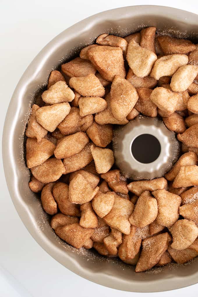 overhead photo of bundt pan full of cinnamon and sugar coated biscuits on a white surface