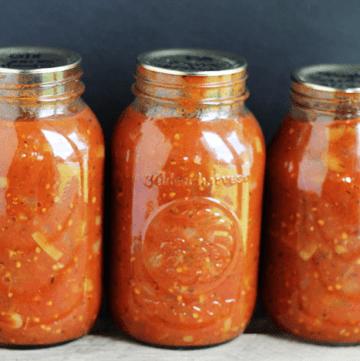 Three tangy jars of spaghetti sauce sitting on a wooden table.