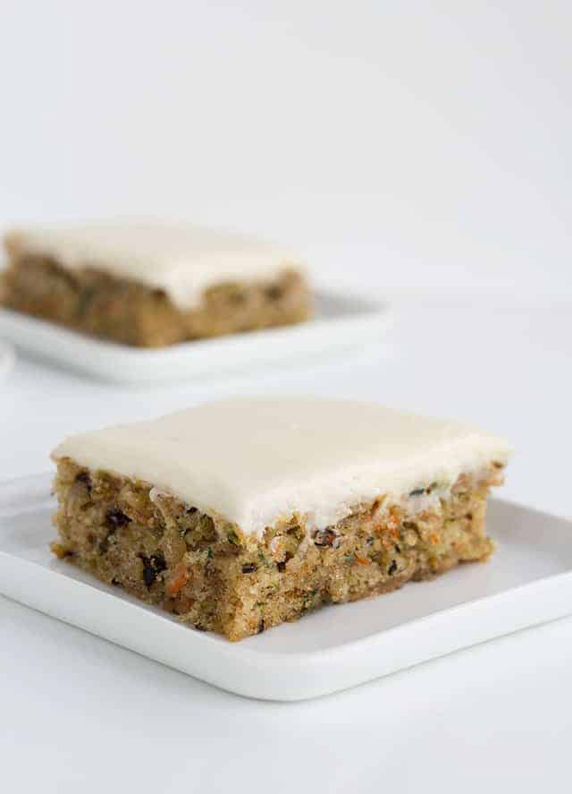 The Best Zucchini Bars - These are the best zucchini bars! They taste like a moist spice cake with a cream cheese frosting. You'll find cinnamon, shredded zucchini and carrots, and walnuts in these bars. This is one of the best zucchini recipes I can think of! #cookiedoughandovenmitt #zucchini #barrecipe #dessertfoodrecipes #dessertrecipes #creamcheesefrosting #frosting zucchini bars topped with cream cheese frosting