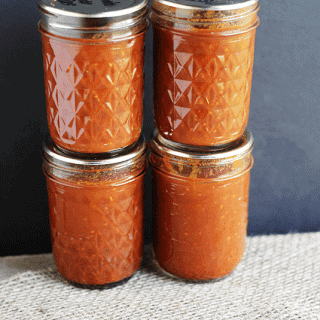 Three jars of tomato paste sitting on top of a cloth.