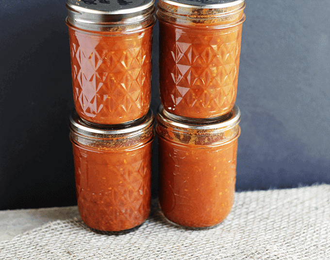 Three jars of tomato paste sitting on top of a cloth.