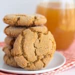 apple cider snaps stacked on a white plate with a cookie on its side