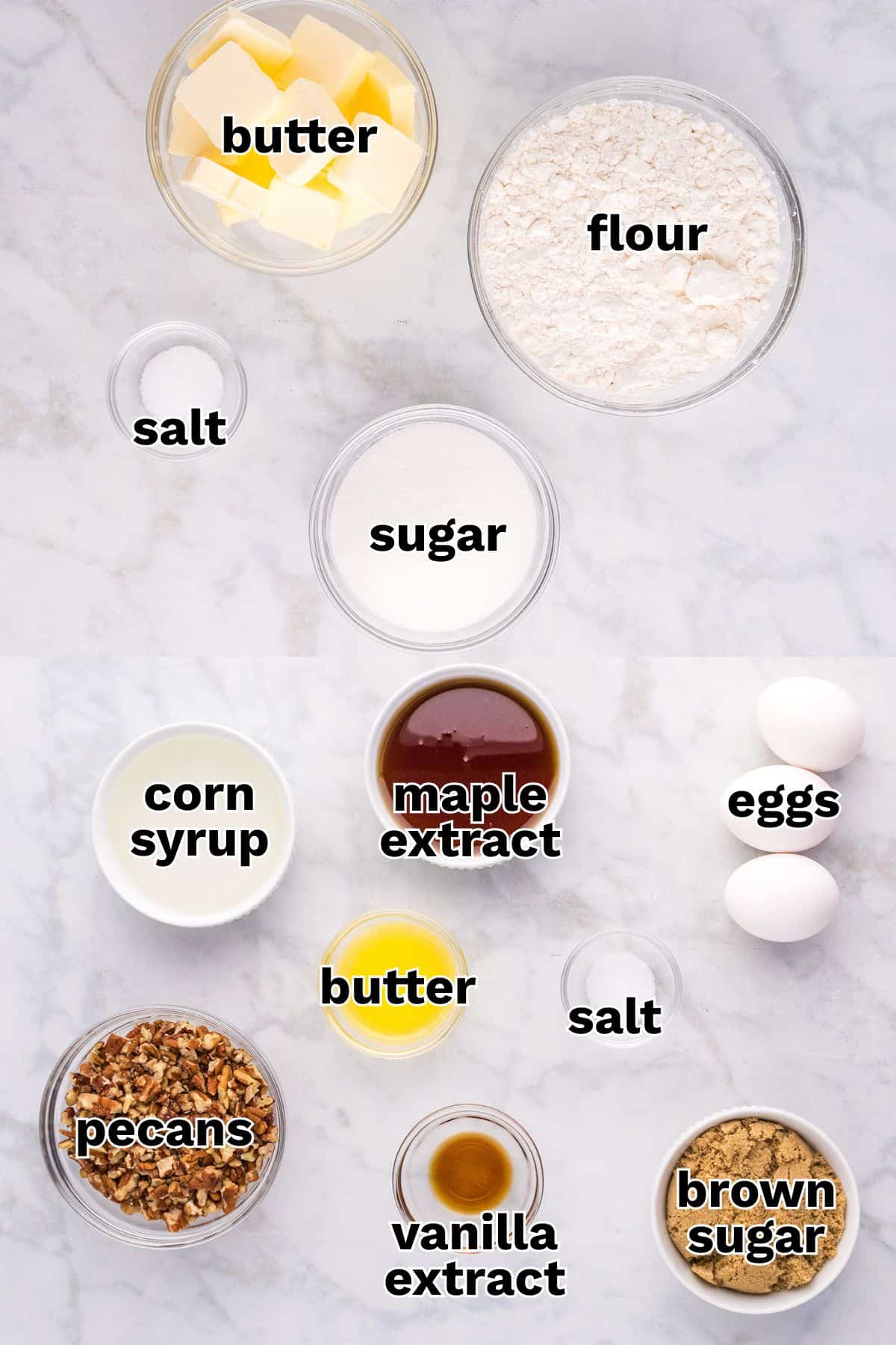Assorted baking ingredients for Pecan Pie Bars, including butter, flour, salt, sugar, corn syrup, maple extract, eggs, pecans, vanilla extract, and brown sugar, are beautifully arranged on a marble surface.