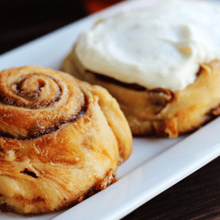 Three cinnamon rolls are positioned on a white plate.