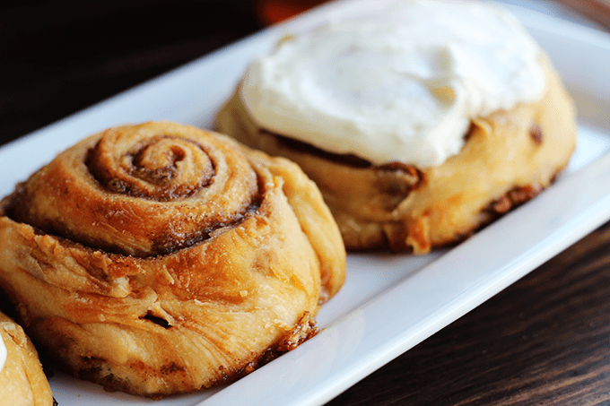 Three cinnamon rolls are positioned on a white plate.