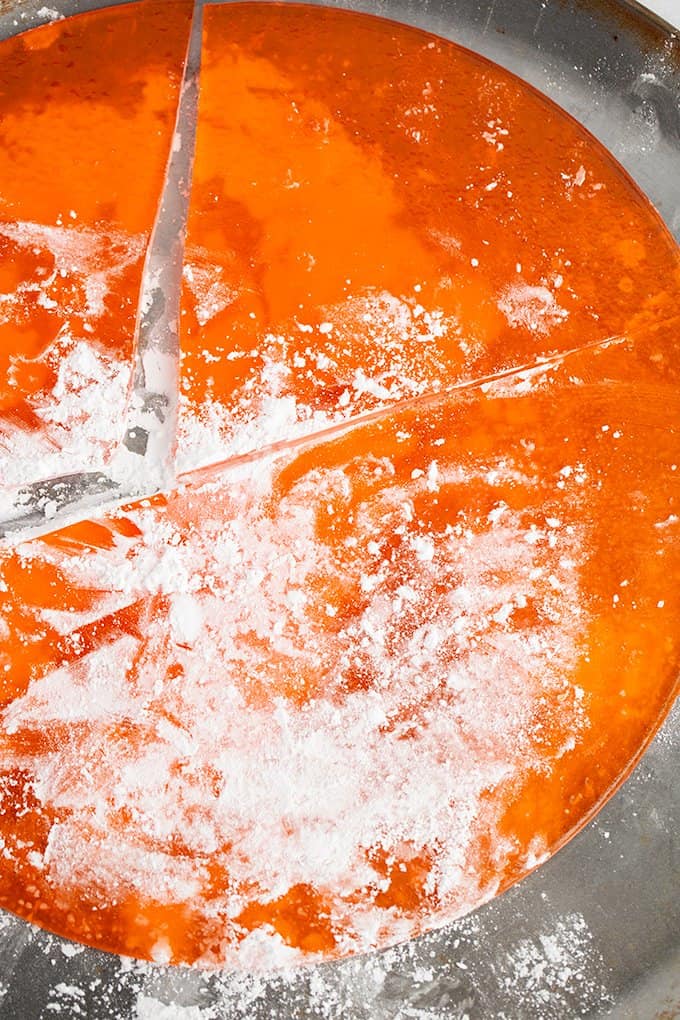 https://www.cookiedoughandovenmitt.com/wp-content/uploads/2013/12/How-To-Make-Rock-Candy-4-Orange-Rock-Candy-Harden-On-Round-Pan-with-Powdered-Sugar-and-Broken-in-pieces.jpg