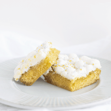 Lemon bars made with lemon cake mix, served on a plate next to a lemon.