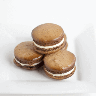 Four Root Beer macarons on a white plate.