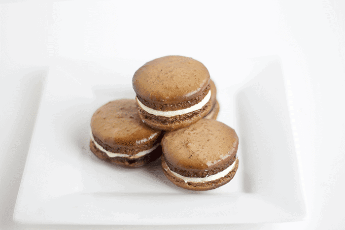 Four Root Beer macarons on a white plate.
