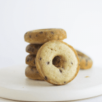 A stack of baked chocolate chip donuts on a white plate.