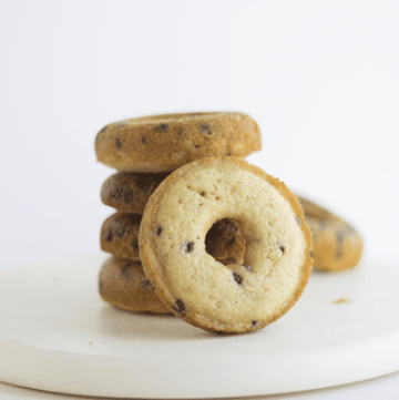 A stack of baked chocolate chip donuts on a white plate.