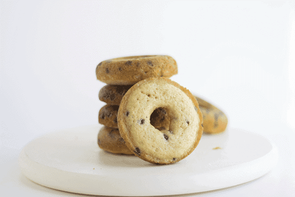 A stack of baked chocolate chip donuts on a white plate.