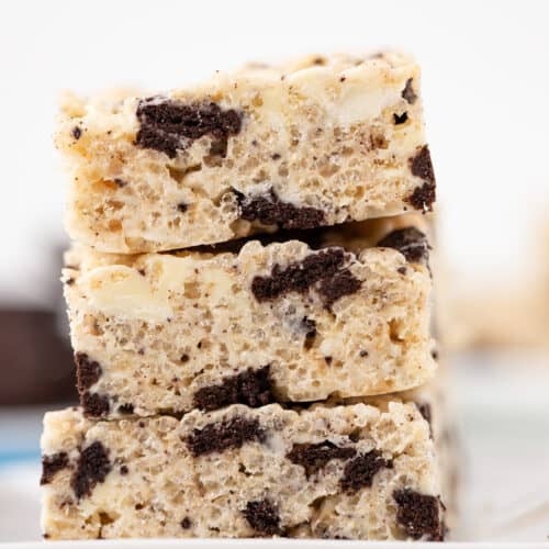 Three stacked Cookies & Cream Rice Crispy Treats with visible chocolate cookie pieces rest on a white plate.
