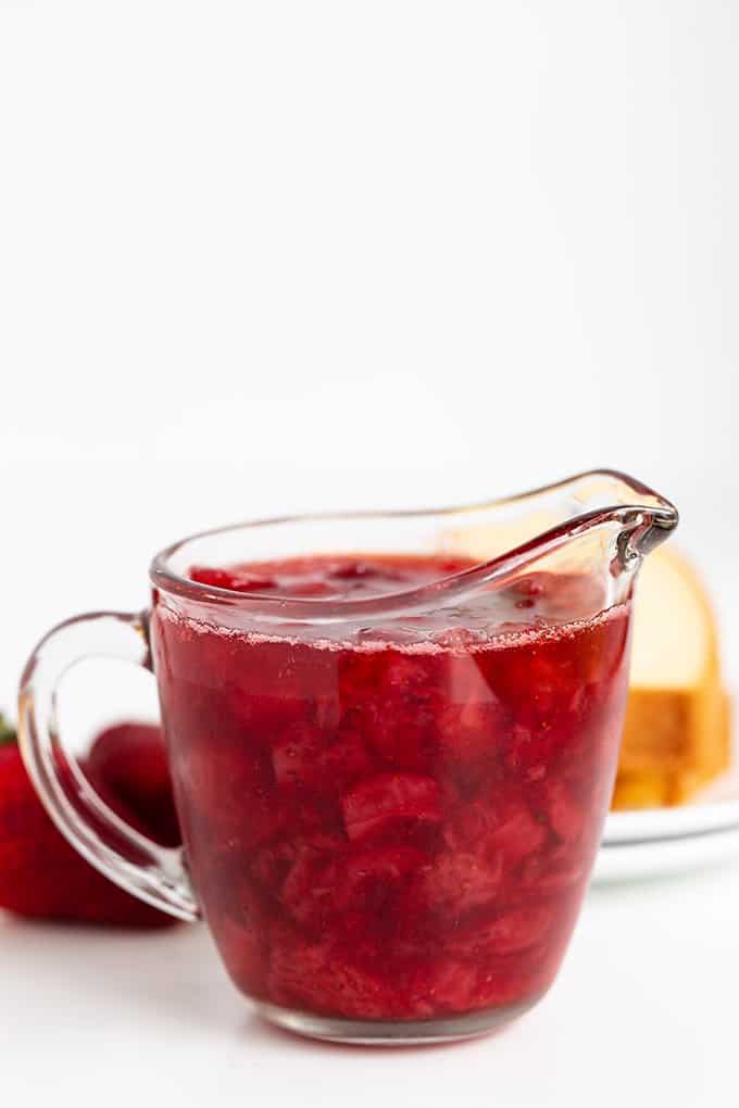 serving glass full of strawberry syrup on a white surface