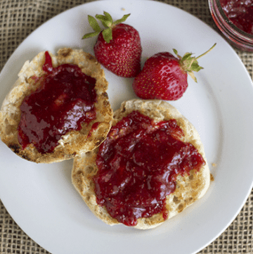 Strawberry Rhubarb Jam on a white plate with strawberries.