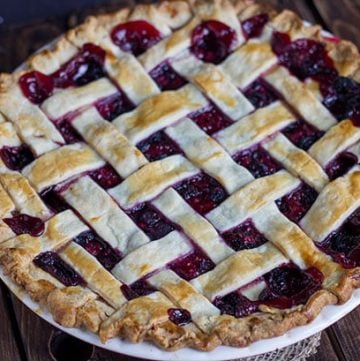 A Mixed Berry Pie with a lattice top on a wooden table.
