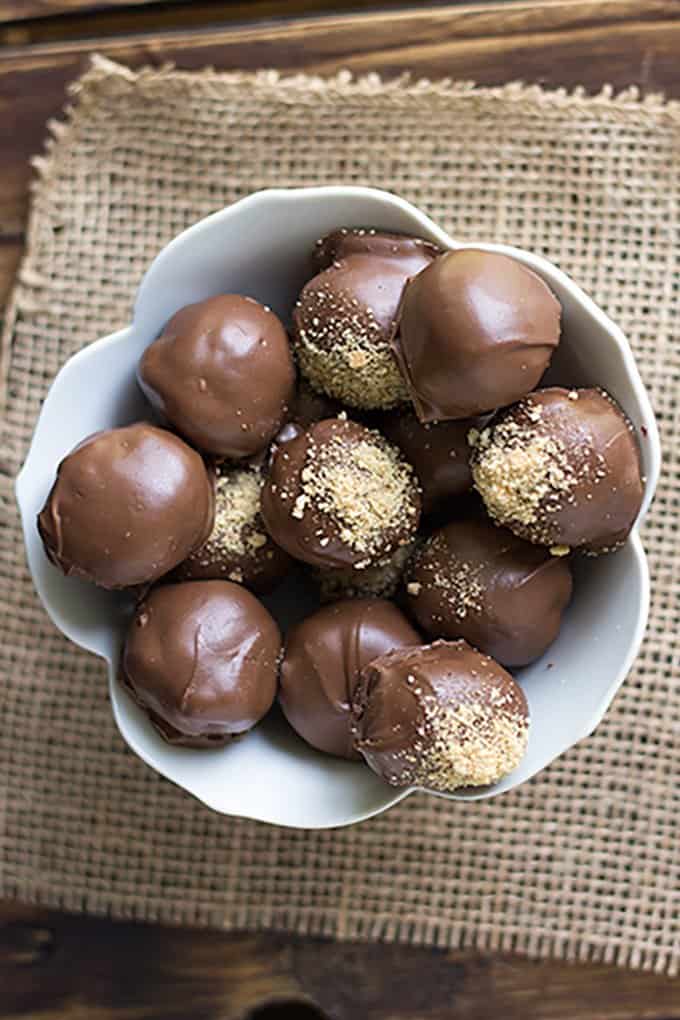 overhead image of the smores truffles in a white bowl with burlap under it on a wooden board