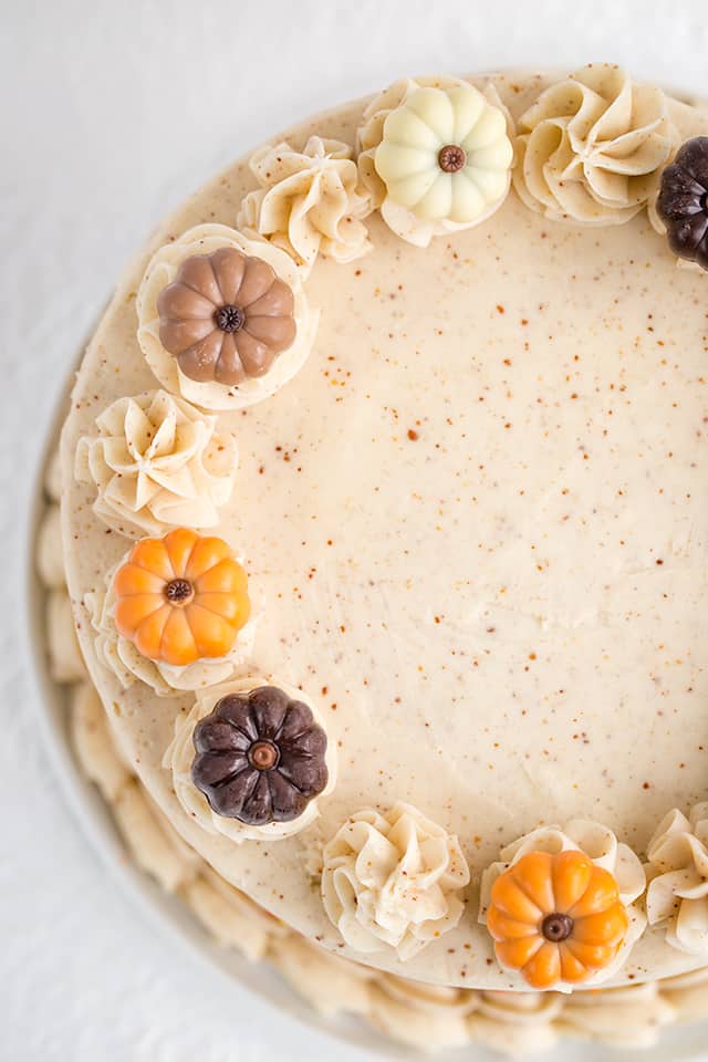 Pumpkin Cake Recipe - This moist Pumpkin Spice Cake with Brown Butter Frosting is one of the tastiest fall desserts! The brown butter frosting has specks in it and tastes sweet and nutty. The pumpkin cake is packed full of spices and topped with adorable chocolate pumpkin truffles. #pumpkin #cake #falldesserts #cookiedoughandovenmitt overhead photo of pumpkin spice cake showing the colorful pumpkin truffles