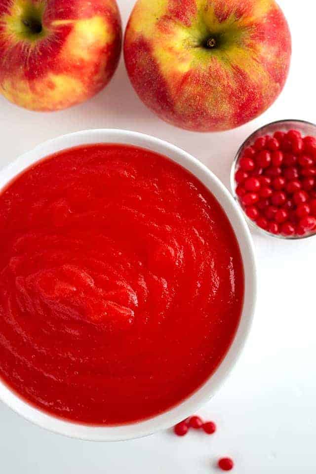 overhead photo of red hot applesauce, candies, and apples