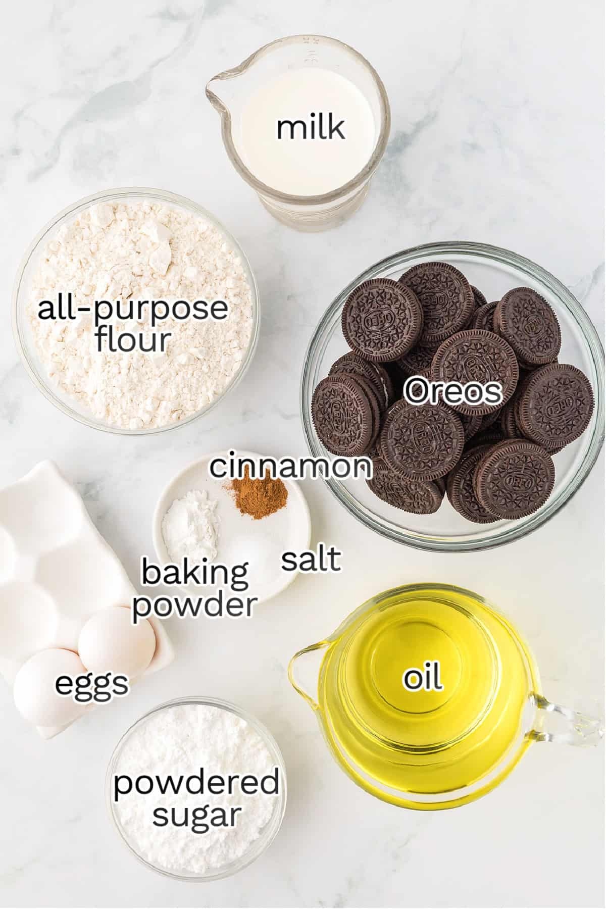 Top-down view of ingredients in bowls and containers for making deep fried Oreos, including milk, all-purpose flour, Oreos, eggs, powdered sugar, oil, baking powder, salt, and cinnamon on a marble surface.