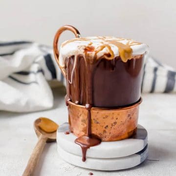 Glass of hot cocoa dripping on a coaster with a spoon