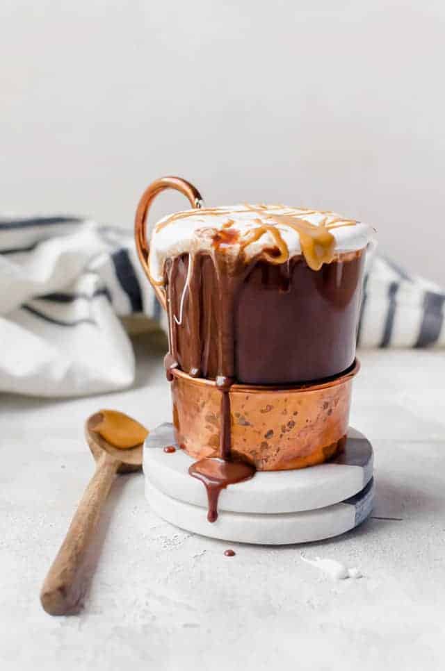 Glass of hot cocoa dripping on a coaster with a spoon